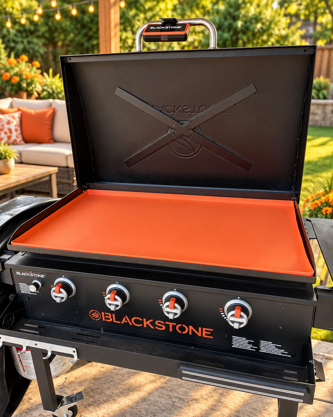 Orange OZG silicone mat covering a griddle on a sunny backyard patio
